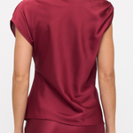 A woman shown from the back wearing a satin-like burgundy top with cap sleeves and a matching skirt against a plain light background.