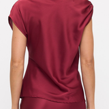 A woman shown from the back wearing a satin-like burgundy top with cap sleeves and a matching skirt against a plain light background.