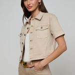 Woman wearing a beige denim jacket and pants on a plain background