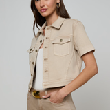 Woman wearing a beige denim jacket and pants on a plain background