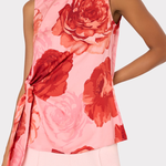 Woman wearing a sleeveless top with red floral pattern on a light pink background