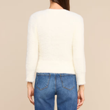 A woman shown from the back wearing a cream-colored, long-sleeve fuzzy knit top and blue jeans against a solid beige background.