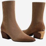 A pair of women's ankle boots in a warm taupe-brown suede-like material, featuring a low block heel and a light wood-textured heel accent, shown against a plain white background.