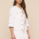 Woman wearing a white button-up jacket and skirt set against a beige background