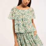 Woman wearing a floral top and skirt on a white background