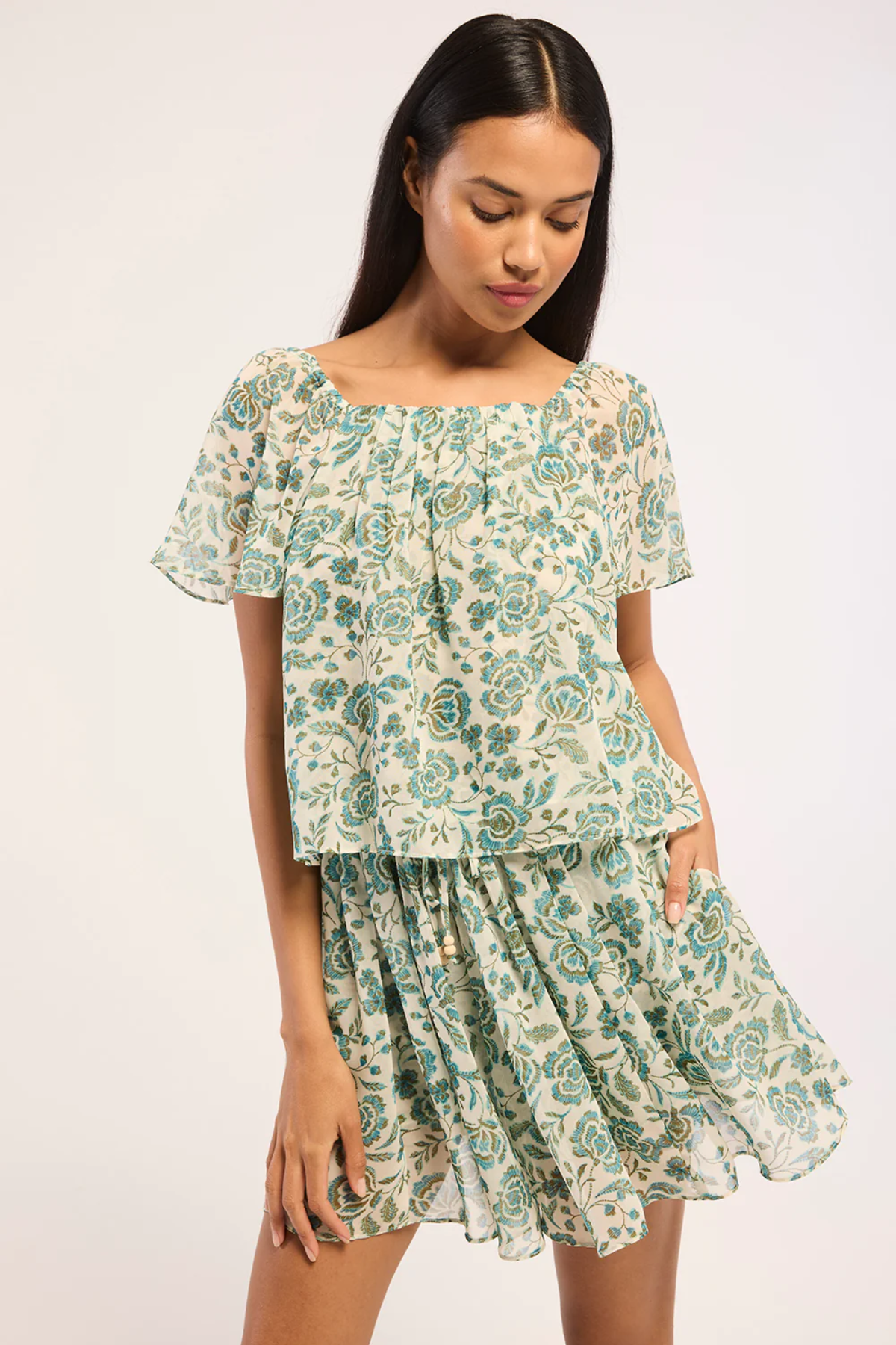 Woman wearing a floral top and skirt on a white background