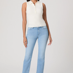 Woman wearing a white sleeveless top and light blue jeans on a white background