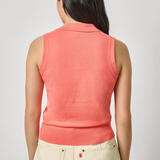 Person wearing a coral sleeveless top and beige pants on a light gray background