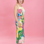 Woman wearing a colorful floral dress against a pink background