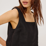 Woman wearing a black sleeveless top against a white background