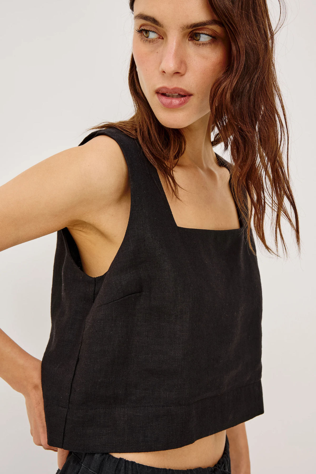Woman wearing a black sleeveless top against a white background
