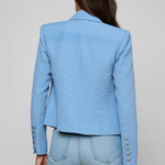Person wearing a light blue blazer and jeans on a plain background