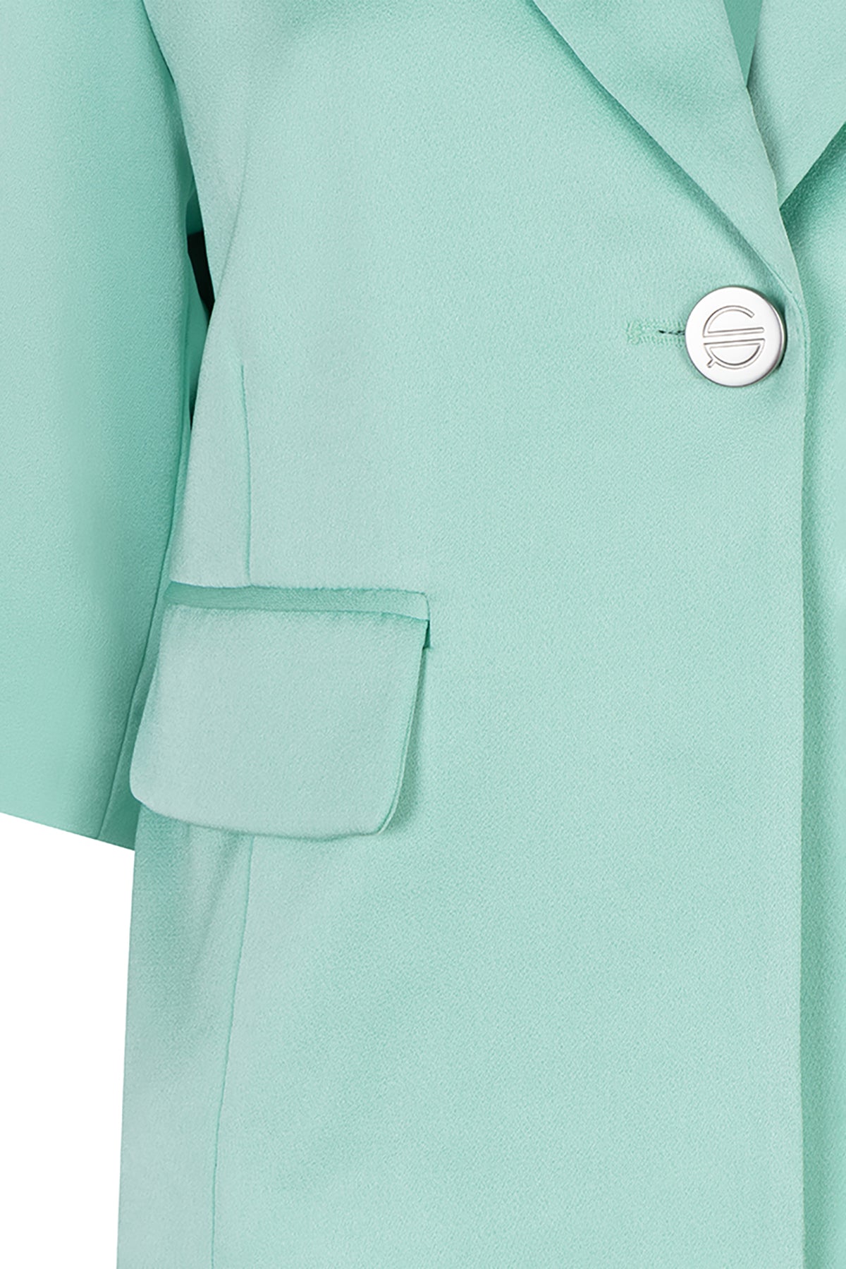 Close-up of a light green coat with a button and pocket detail.