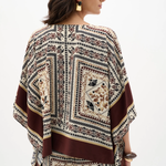 Woman wearing a patterned poncho against a white background