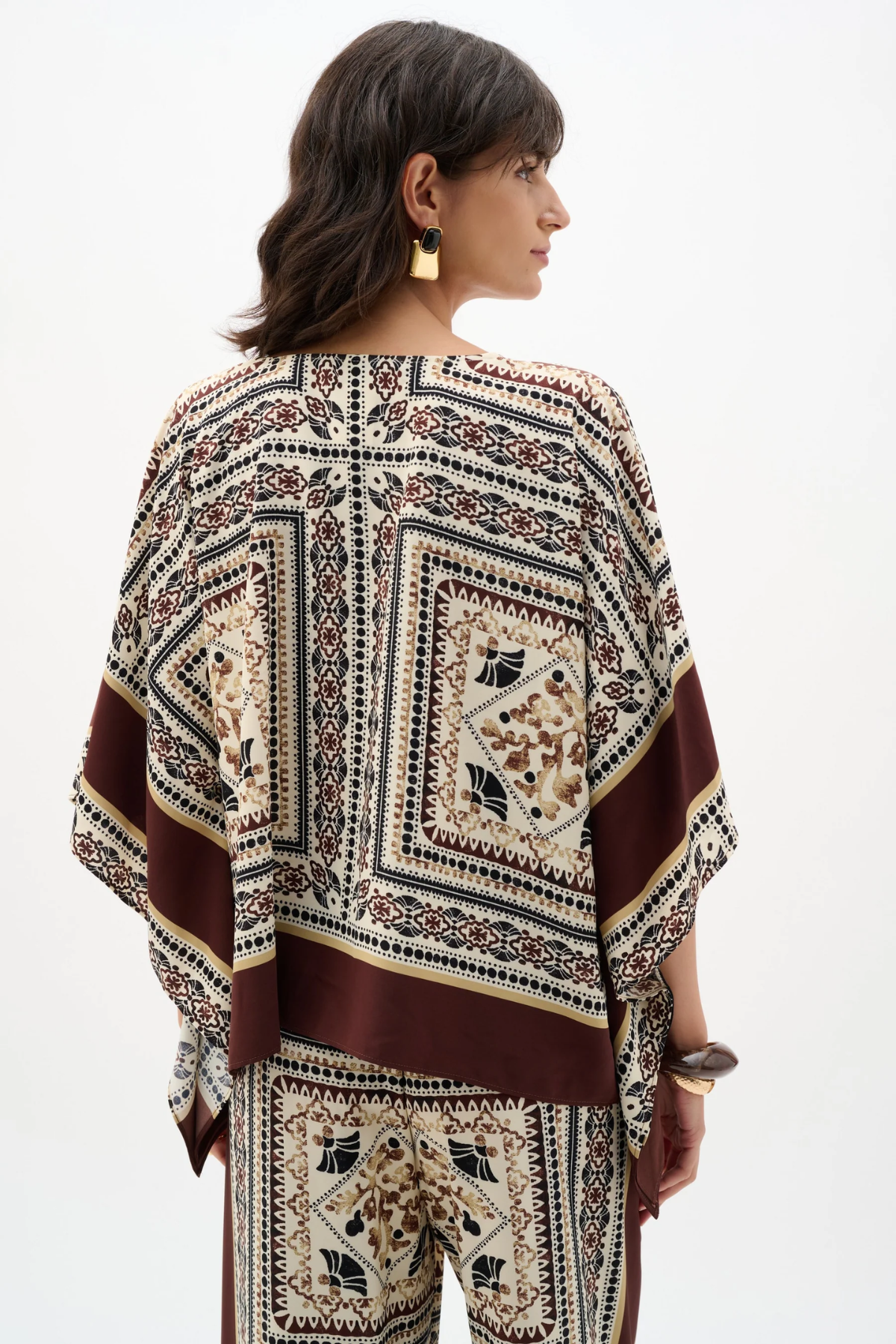 Woman wearing a patterned poncho against a white background