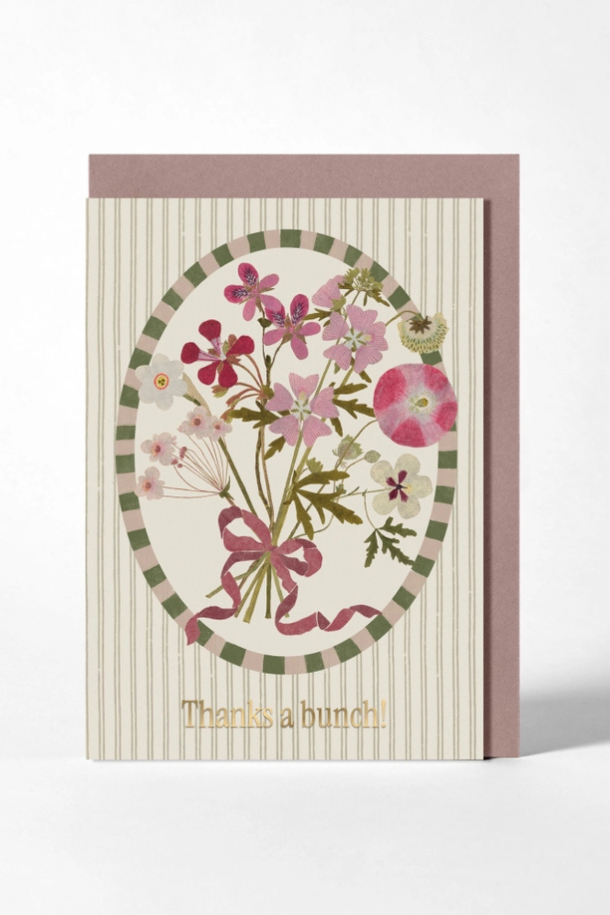 A floral greeting card with a striped cream background, an oval bouquet illustration in pink, green, and beige tones, and the text 'Thanks a bunch!' at the bottom, shown with a mauve envelope behind it on a light gray background.