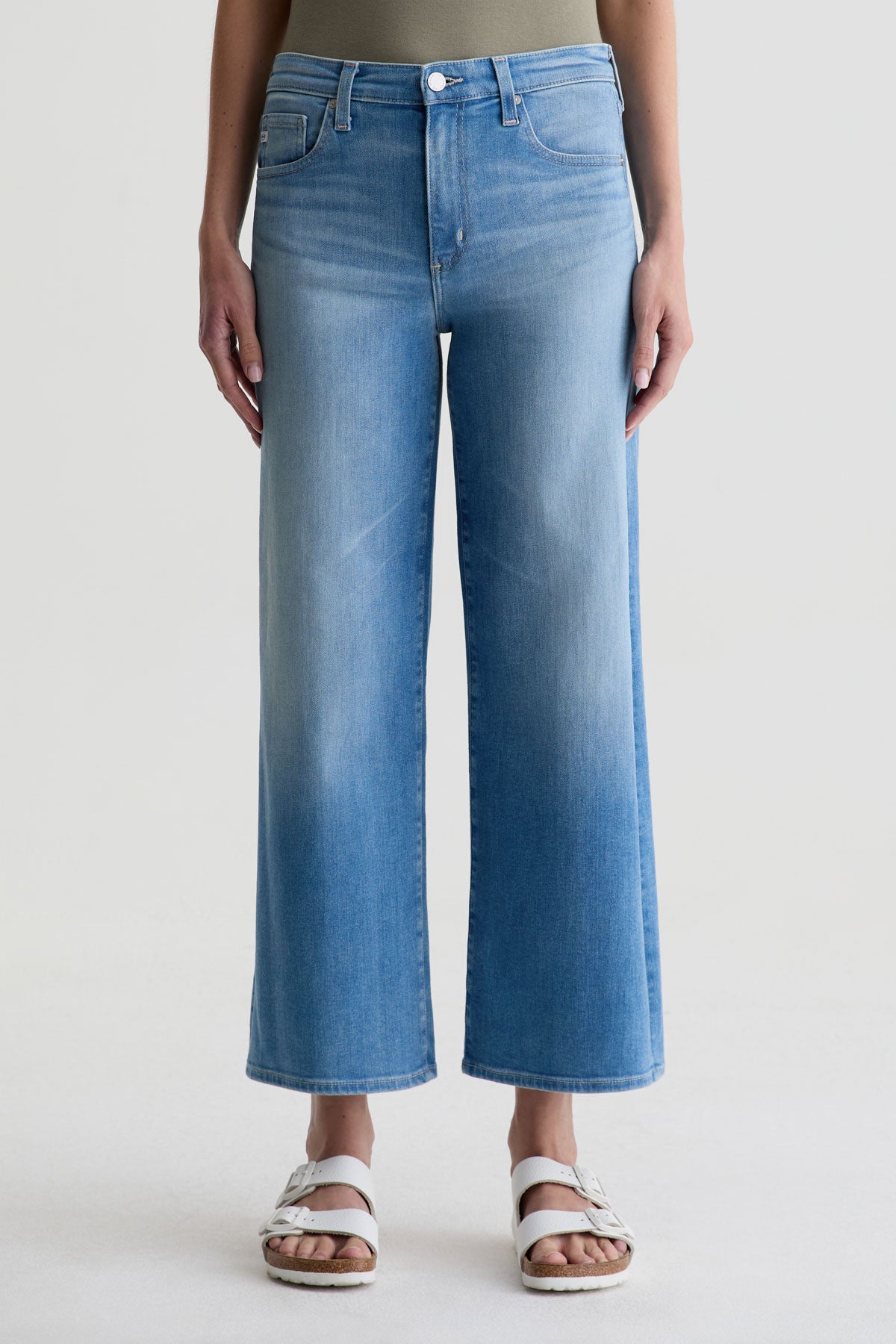 Person wearing blue jeans on a plain background