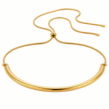A gold-toned metal necklace with a thick, polished curved bar and a thin adjustable snake chain closure, shown on a plain white background.