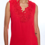 Red sleeveless top with floral lace details worn by a person on a white background