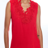 Red sleeveless top with floral lace details worn by a person on a white background