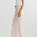 Person wearing a white tank top and light pink pants on a plain background