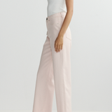 Person wearing a white tank top and light pink pants on a plain background
