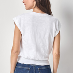 Woman wearing a white top and blue jeans against a plain background