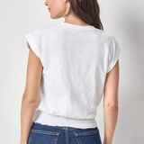 Woman wearing a white top and blue jeans against a plain background