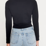 Person wearing a black long-sleeve top and light blue jeans on a white background