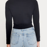 Person wearing a black long-sleeve top and light blue jeans on a white background