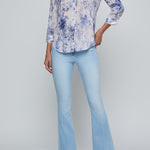 Woman wearing a floral blouse and light blue jeans on a gray background