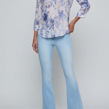 Woman wearing a floral blouse and light blue jeans on a gray background
