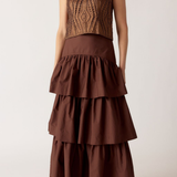 Woman wearing a brown tiered dress with a textured top against a white background