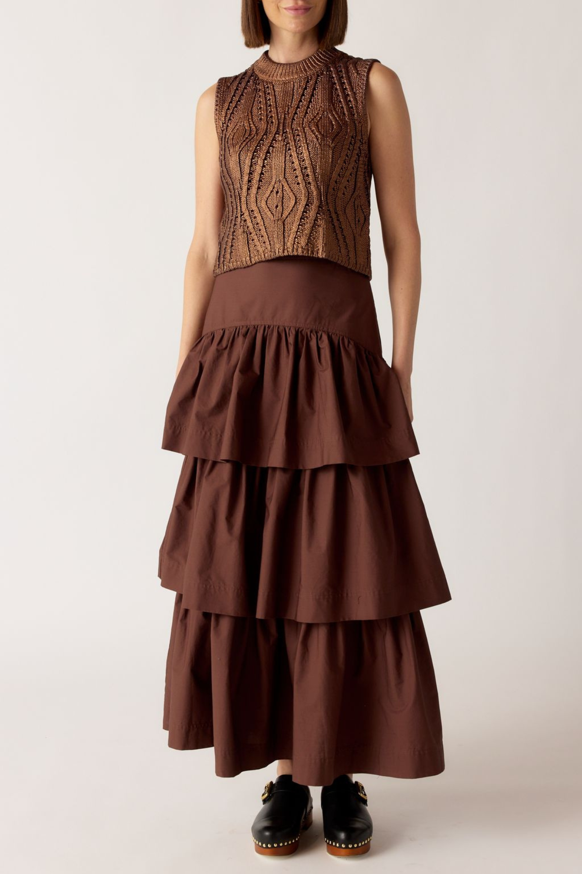 Woman wearing a brown tiered dress with a textured top against a white background