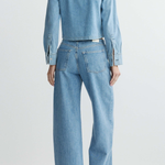 Person wearing a light blue denim jacket and jeans on a white background