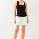 Woman wearing a black tank top and white shorts on a white background