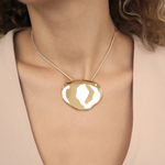 Gold necklace with a large pendant worn by a person