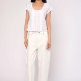 Woman wearing a white top and pants on a plain background