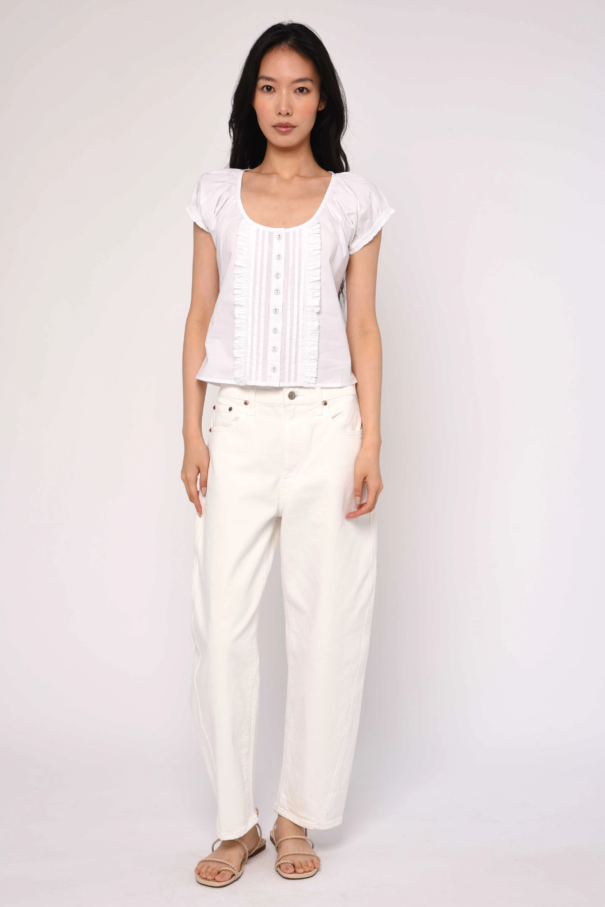 Woman wearing a white top and pants on a plain background