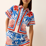 Woman wearing a colorful patterned outfit on a plain background