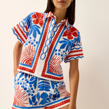 Woman wearing a colorful patterned outfit on a plain background