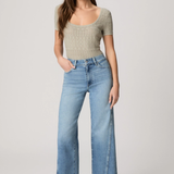 Woman wearing a beige top and light blue jeans on a white background