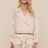 Woman wearing a beige lace jacket over a matching lace dress on a beige background