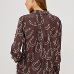 Woman wearing a brown shirt with horseshoe pattern on a white background