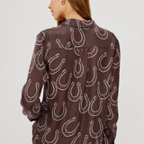 Woman wearing a brown shirt with horseshoe pattern on a white background