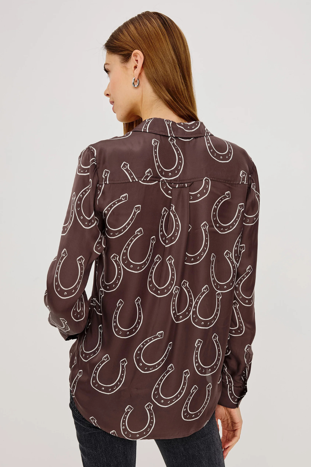 Woman wearing a brown shirt with horseshoe pattern on a white background
