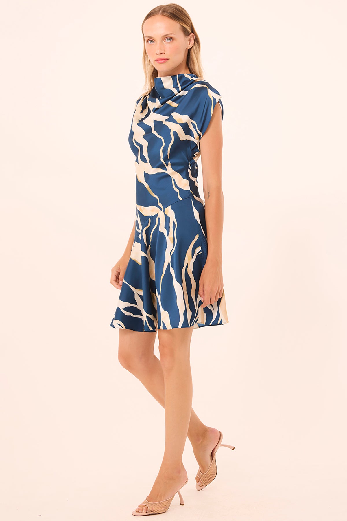Woman wearing a blue and white patterned dress on a beige background