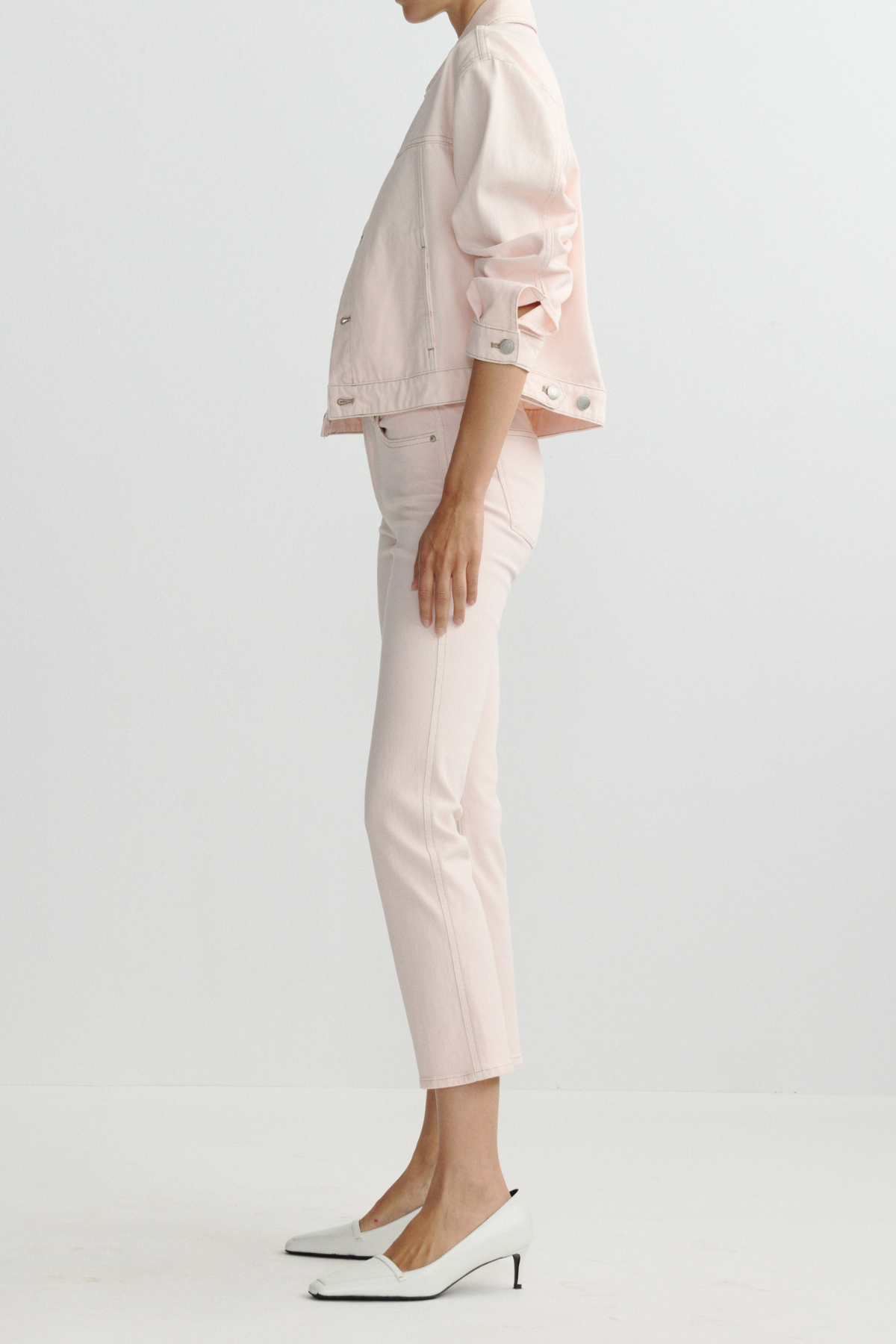 Person wearing a light pink outfit with a jacket and pants on a white background