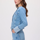 Woman wearing a light blue denim jacket and skirt on a white background