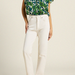 woman in green floral blouse and white denim on tan background 